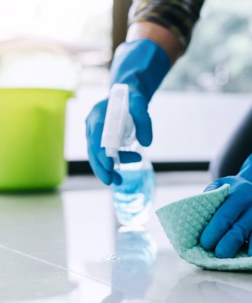 Husband housekeeping and cleaning concept, Happy young man in blue rubber gloves wiping dust using a spray and a duster while cleaning on floor at home.
